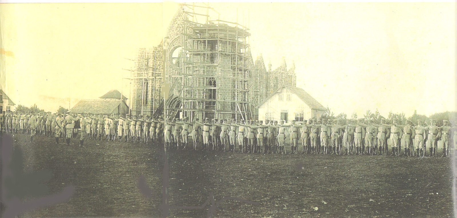 Formação militar do Tiro de Guerra perfilada diante da Catedral em obras, com a torre envolta em andaimes.