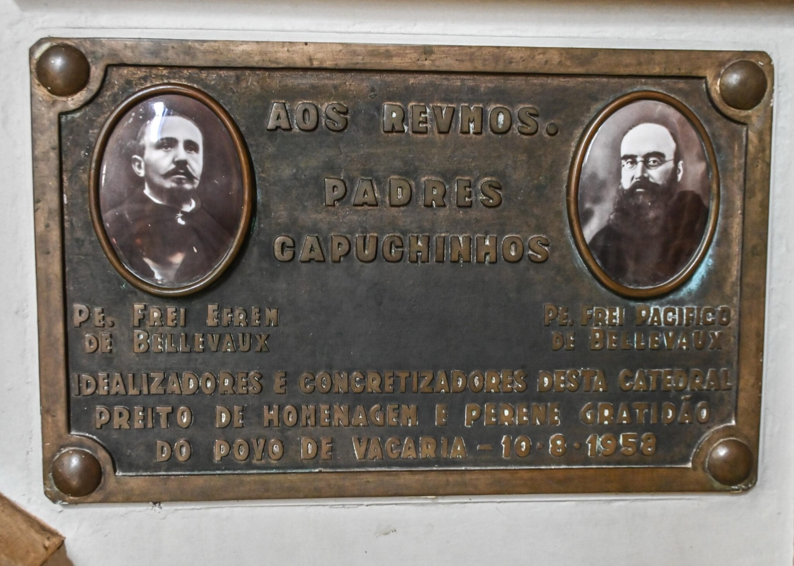 Placa de bronze em homenagem aos padres capuchinhos Pe. Frei Efrem de Bellevaux e Pe. Frei Pacífico de Bellevaux, com seus retratos em medalhões ovais.