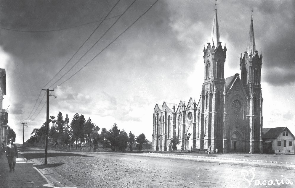 Vista da Catedral concluída, com as duas torres e suas flechas, a partir de uma rua de terra de Vacaria.